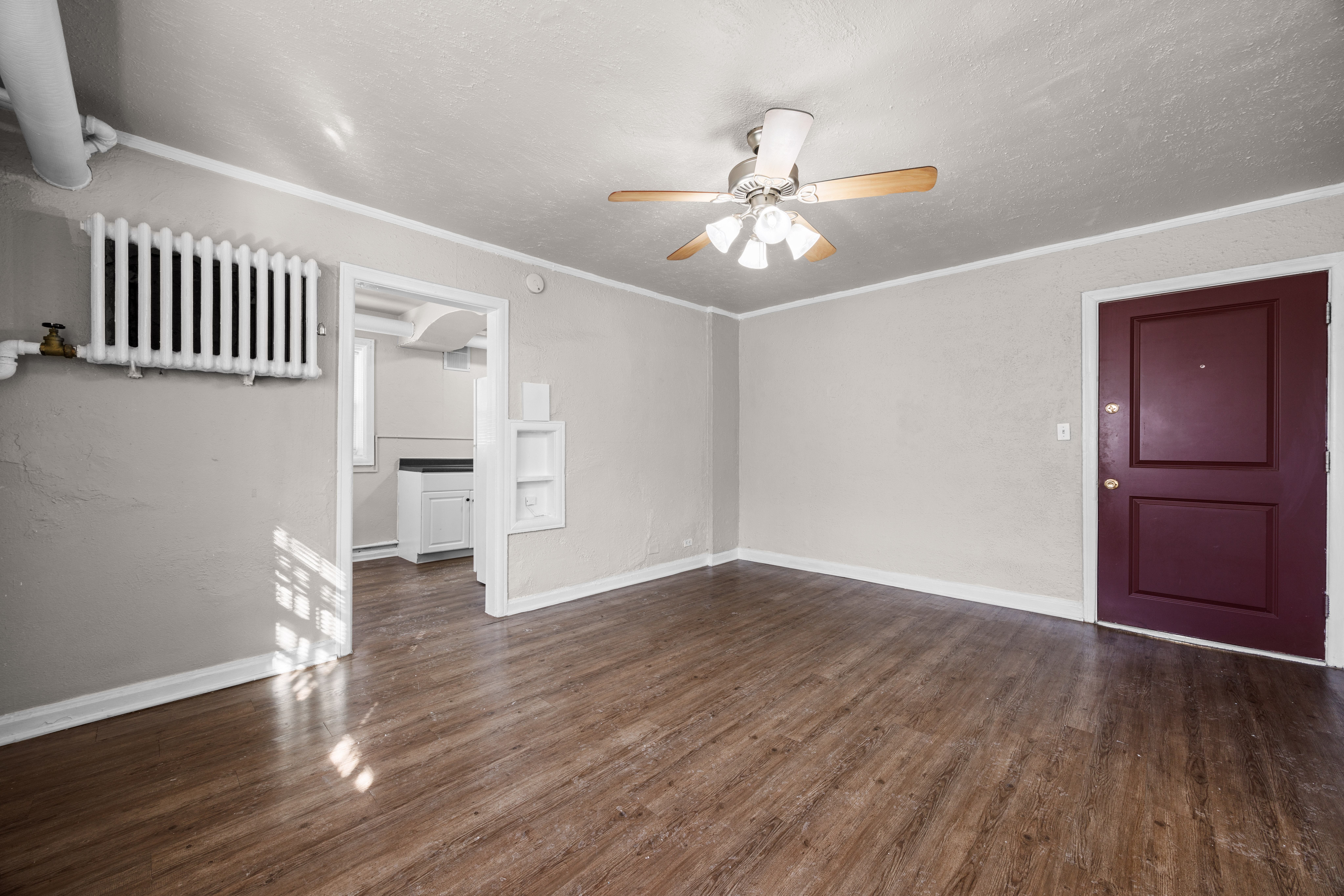 A room with a ceiling fan and a red door.